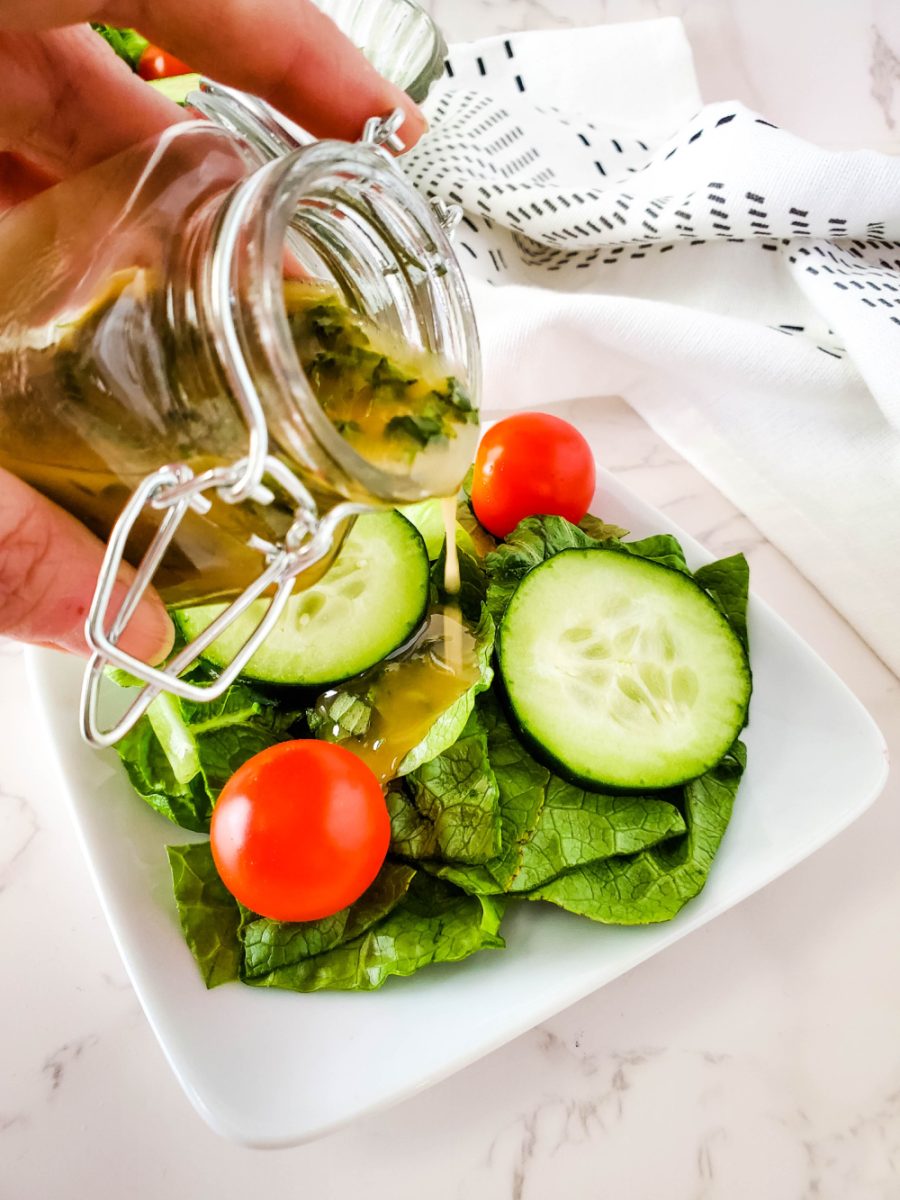 pour Greek dressing over tossed vegetable salad