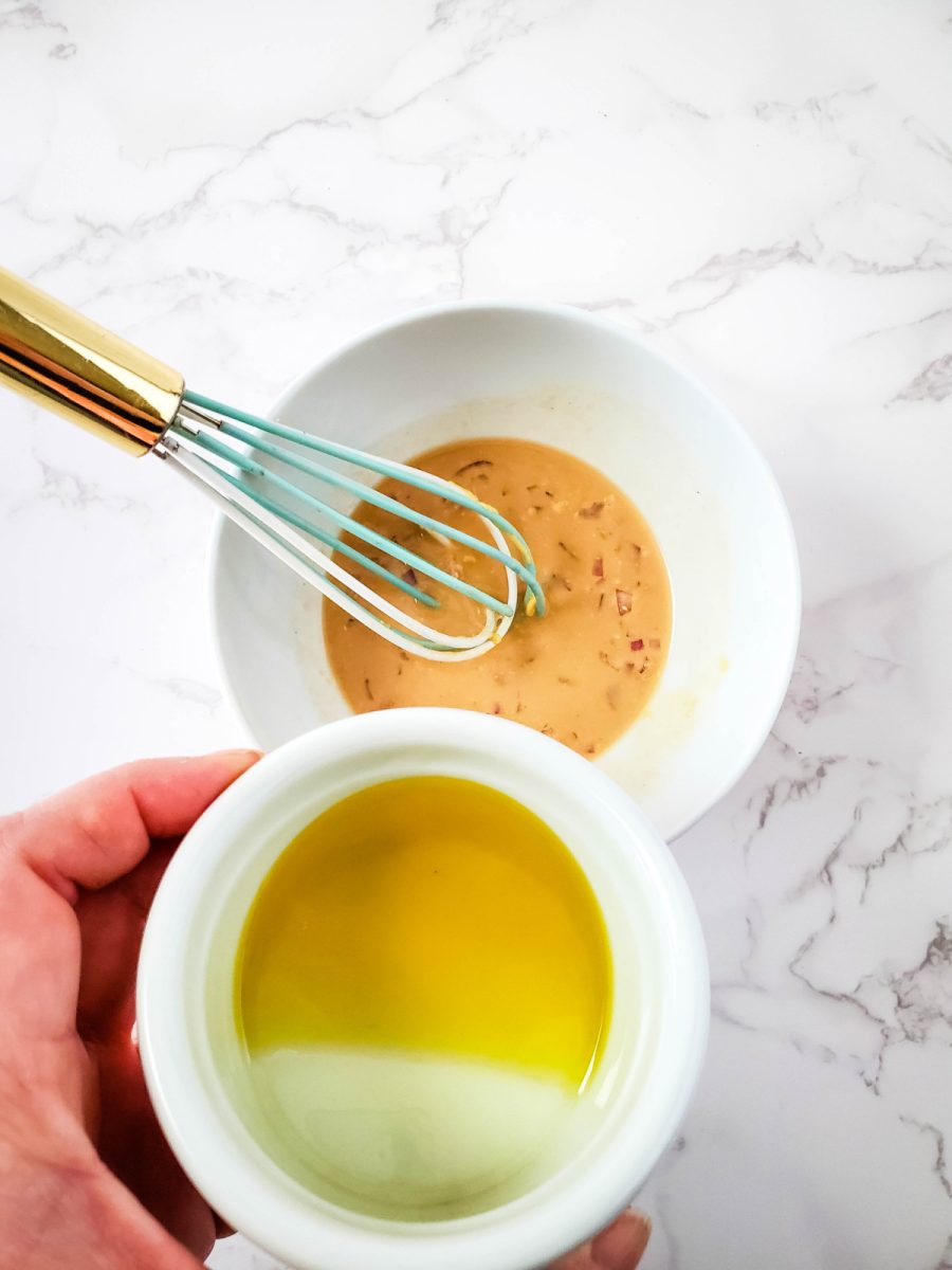 whisking olive oil into dressing