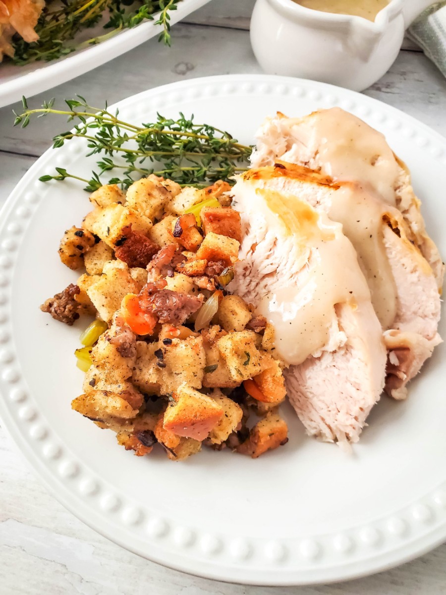 herb roasted turkey slices on plate with gravy and stuffing