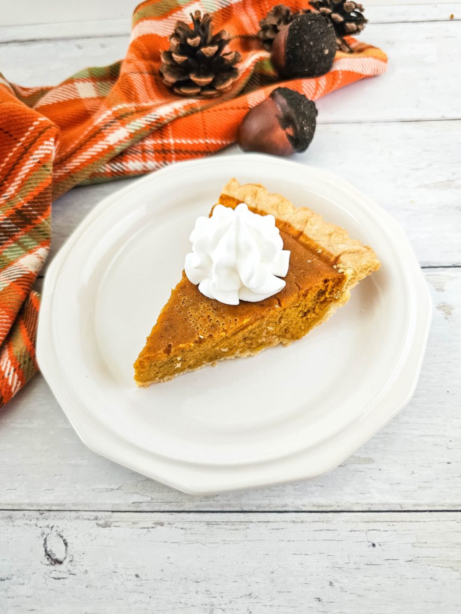 slice of pumpkin pie with whipped cream on white plate