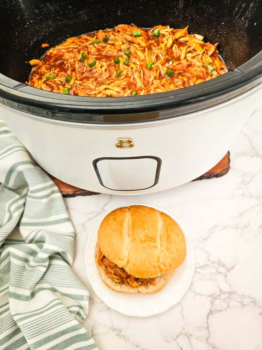 slow cooker with chicken and plate with sandwich