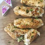 The final plated dish of Broccoli Stuffed Chicken Breasts shown with two foil-wrapped cheese wedges in the upper corner.