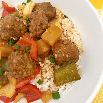 sweet and sour meatballs over rice in white bowl