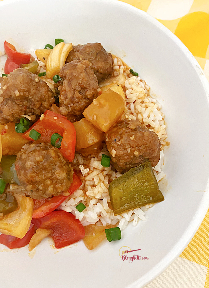 sweet and sour meatballs over rice in white bowl