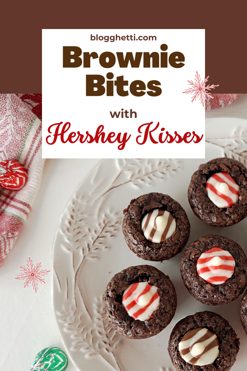 A plate of mini brownie bites, each topped with a Hershey's Kiss candy. The brownies are rich-looking, and the candies add a festive touch. The image is taken from above, and the plate is placed on a white surface.