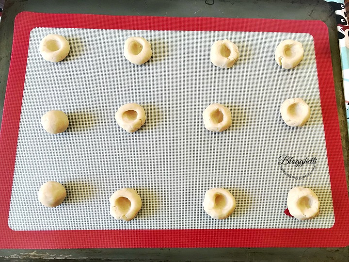 sugar plum thumbprint cookies on baking sheet to be baked