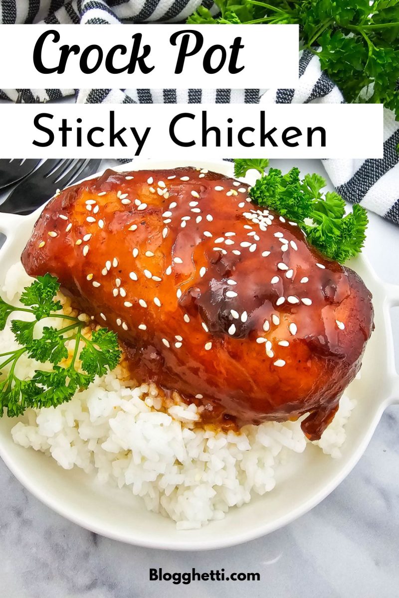 A piece of crock pot sticky chicken, glazed and sprinkled with sesame seeds, rests on a bed of white rice in a white bowl. Fresh parsley sprigs garnish the dish, which is set against a white marble surface with a black and white striped napkin in the background. The recipe title "Crock Pot Sticky Chicken" is overlaid at the top