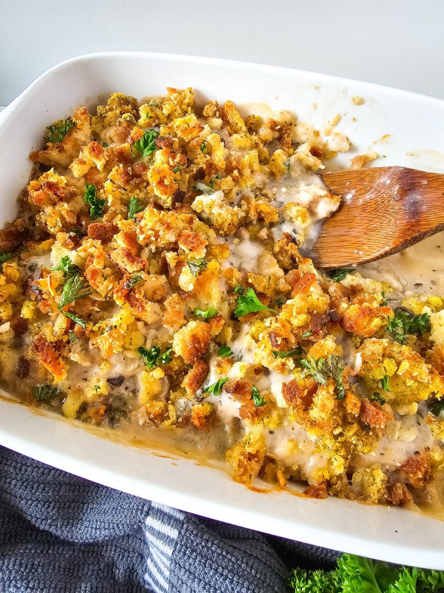 wooden spon in white baking dish with pork casserole