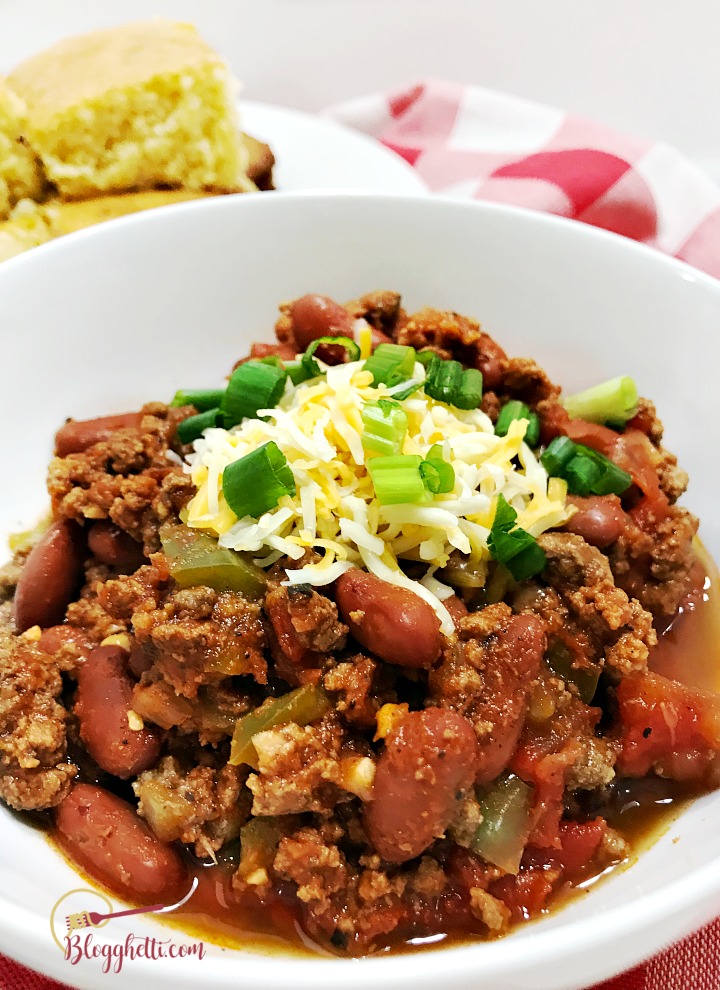 close up of slow cooker chili in white bowl with cornbread
