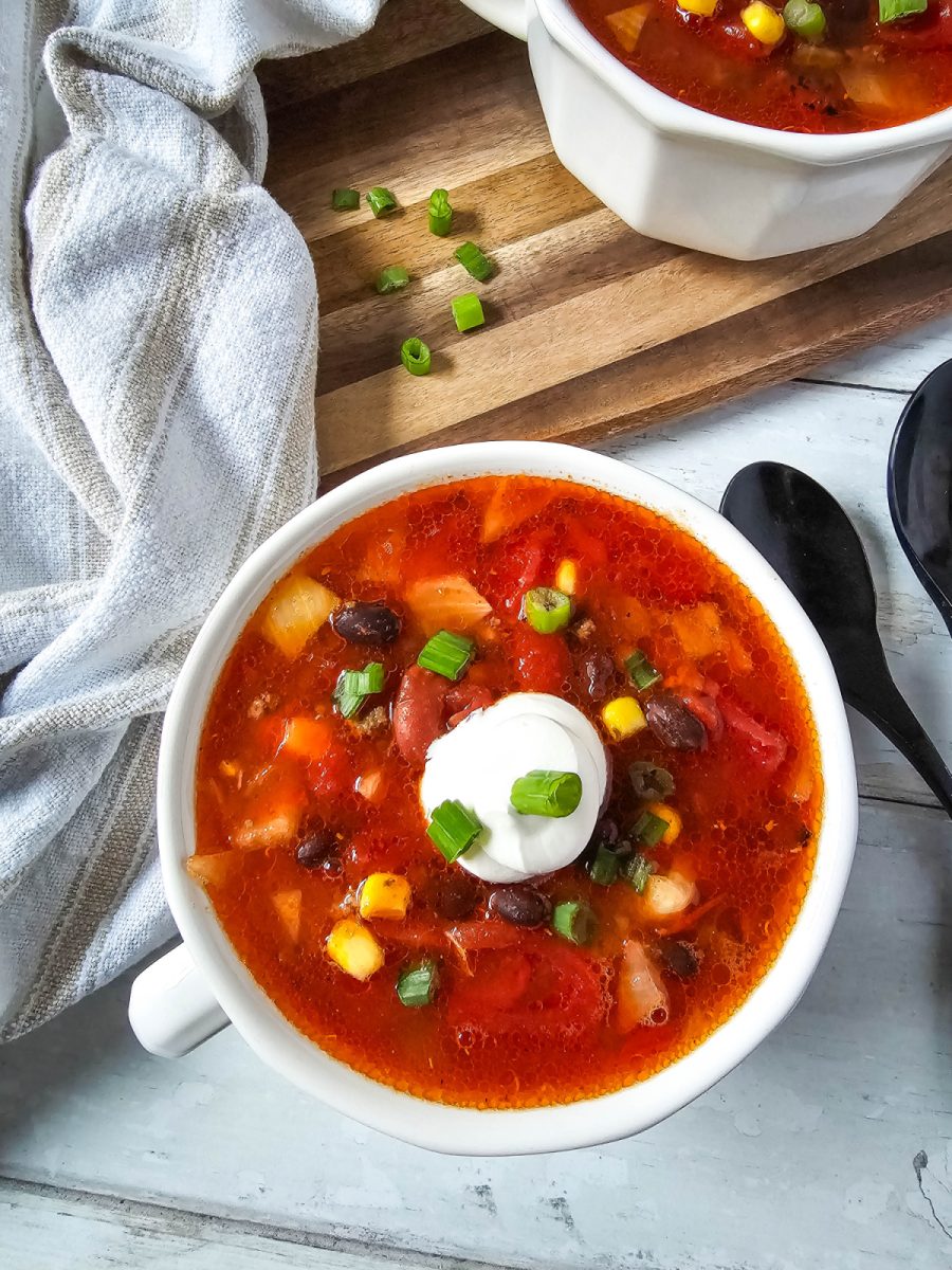 overhead view of slow cooker taco soup in white bowl with toppings