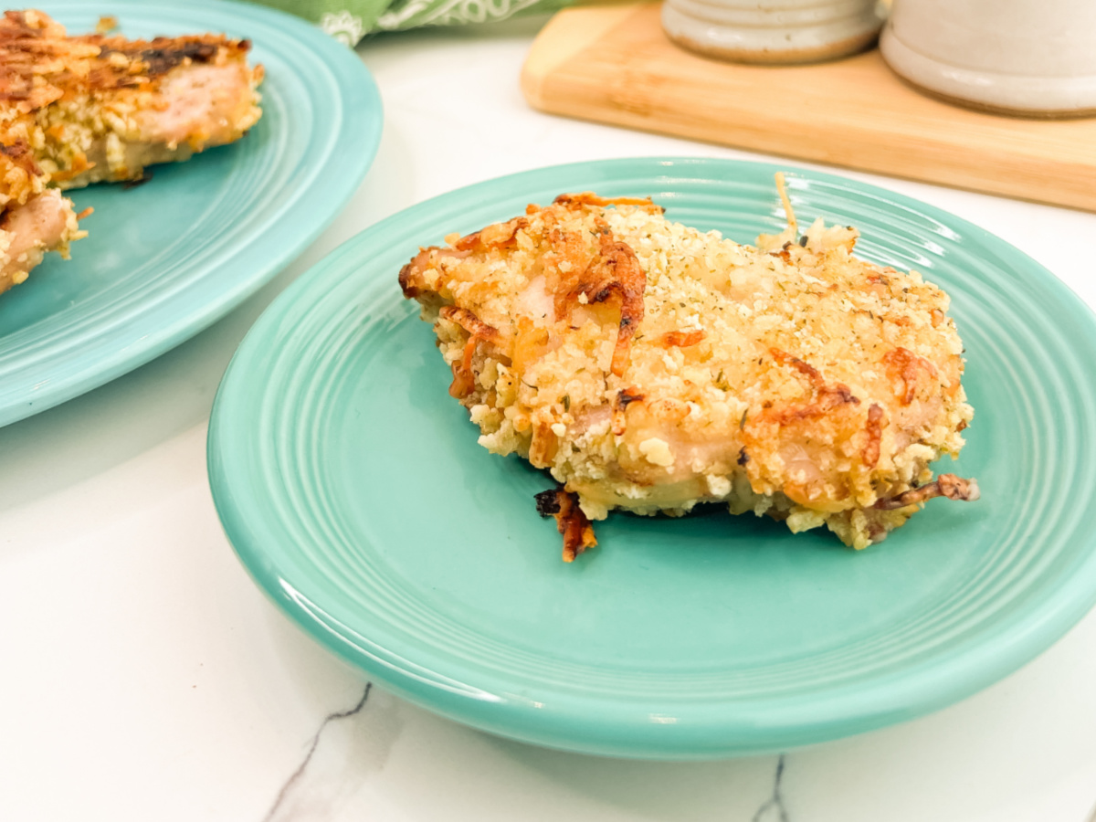 Close-up of a breaded pork chop with a golden, crispy coating served on a turquoise dinner plate.