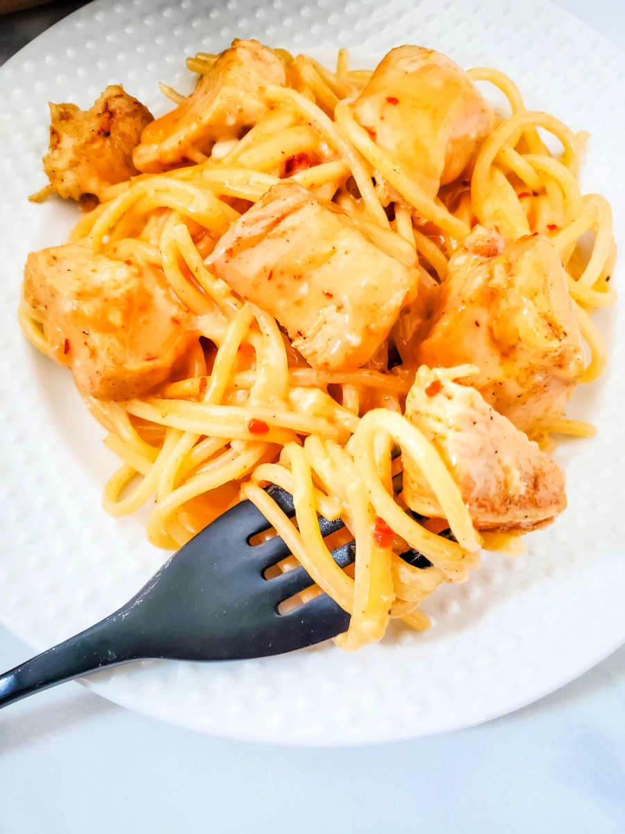 fork with bite of pasta and chicken coated in sauce