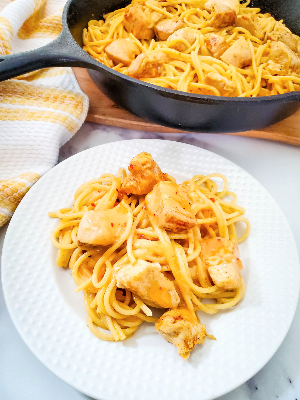 skillet and plate with chicken pasta with bang bang sauce
