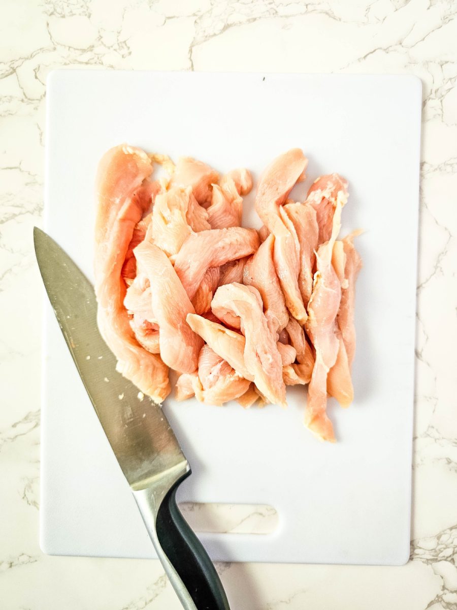 sliced raw chicken strips on cutting board