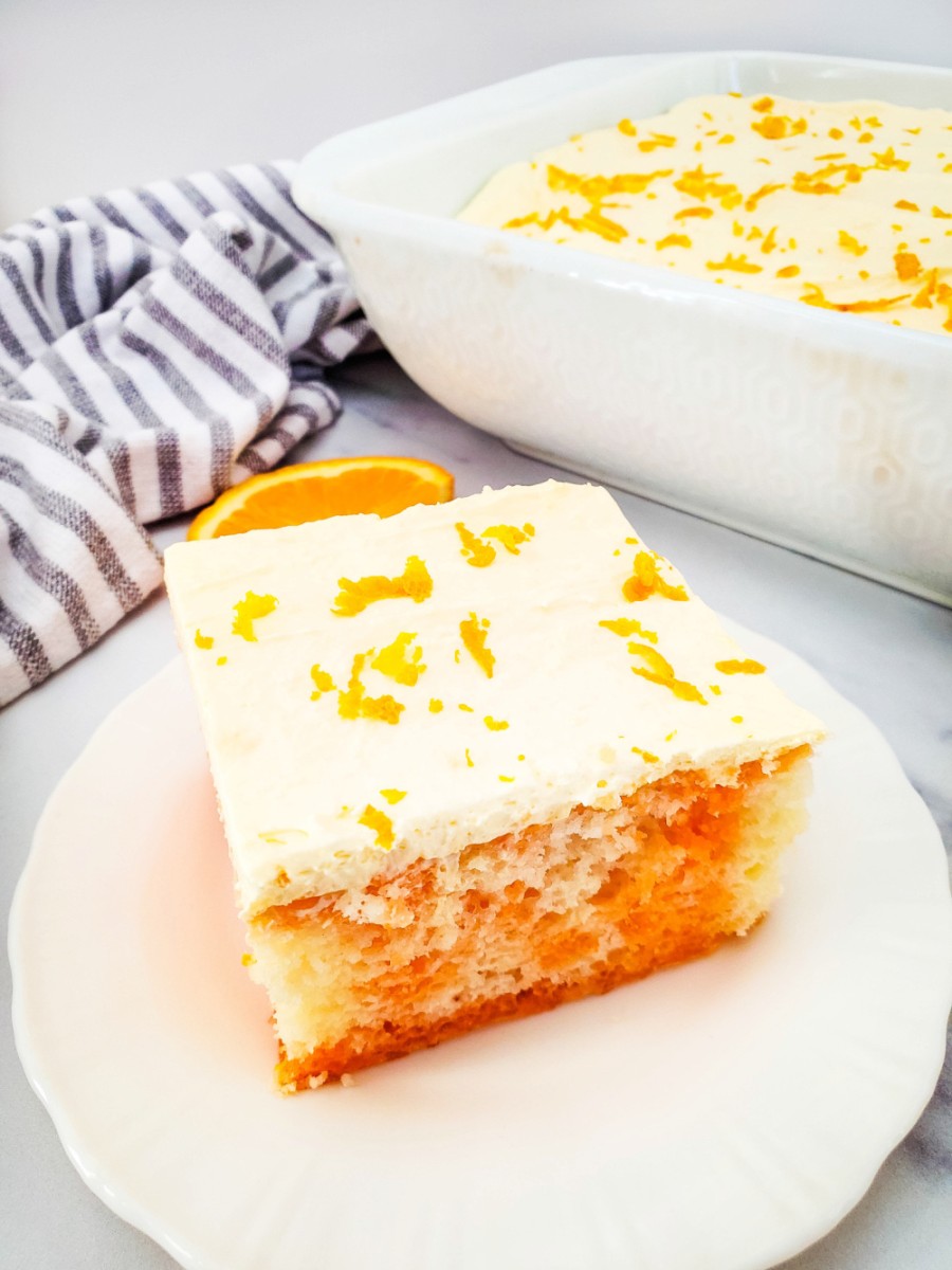 slice of orange cream poke cake in white plate