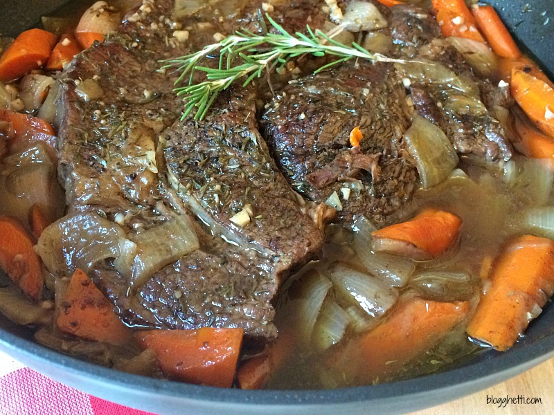 Dutch oven with fork tender perfect pot roast, carrots, onions, and herbs.