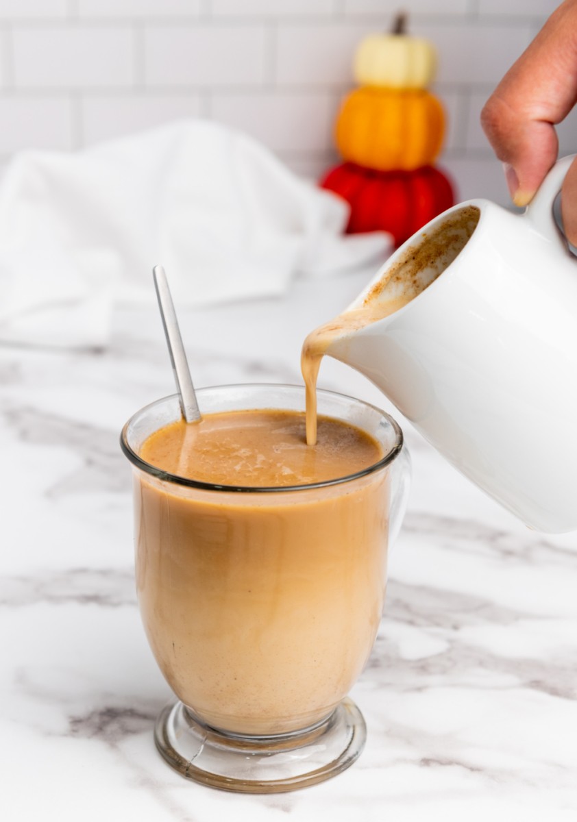 pouring homemade pumpkin spice creamer into coffee cup