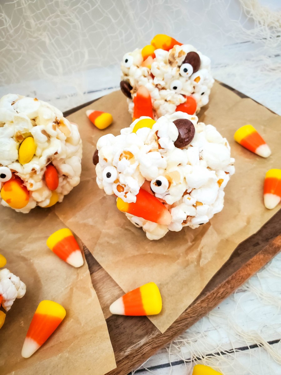 candy popcorn balls on wooden tray for halloween treats