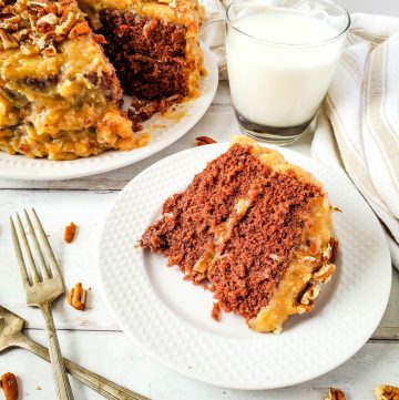 slice of German Chocolate Cake on white plate with glass of milk in background