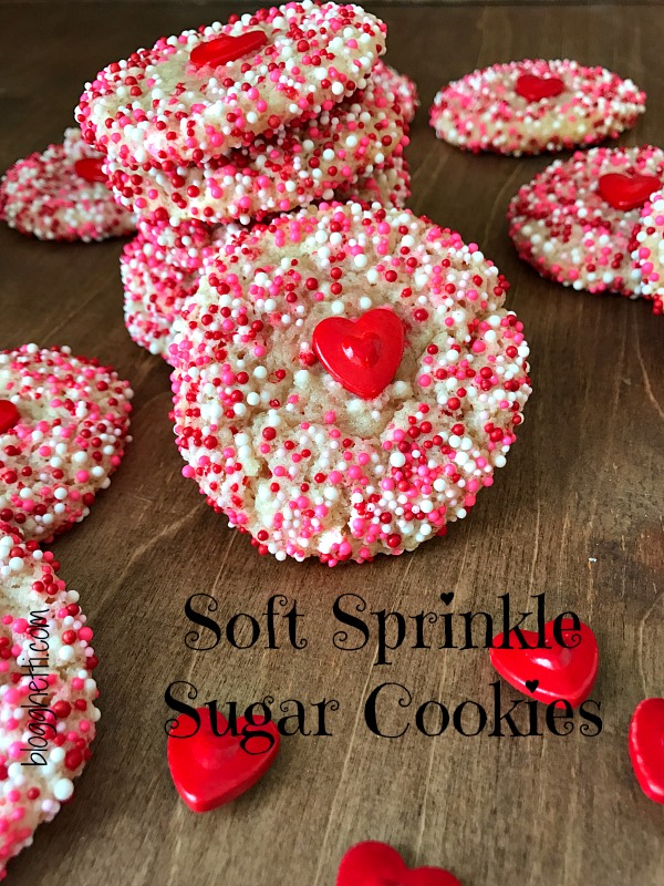 Surprise the Valentines in your life with these super Soft Sprinkle Sugar Cookies that are so easy to bake. No rolling or cutting out of the dough and super simple to decorate with the pink, red, and white sprinkles and a large red heart in the center of the cookie adds even more love to the baked goodness!