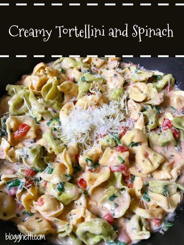 close up of creamy tortellini and spinach meal in a skillet