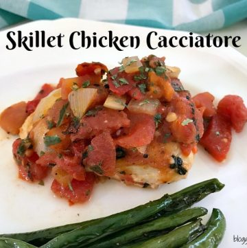 White plate with a serving of skillet chicken Cacciatore with roasted green beans