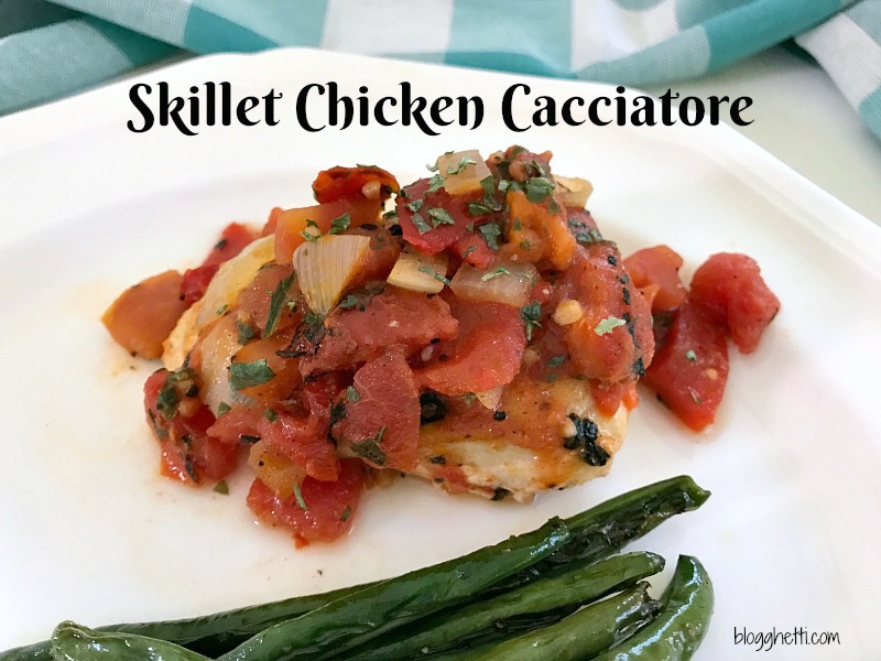 White plate with a serving of skillet chicken Cacciatore with roasted green beans