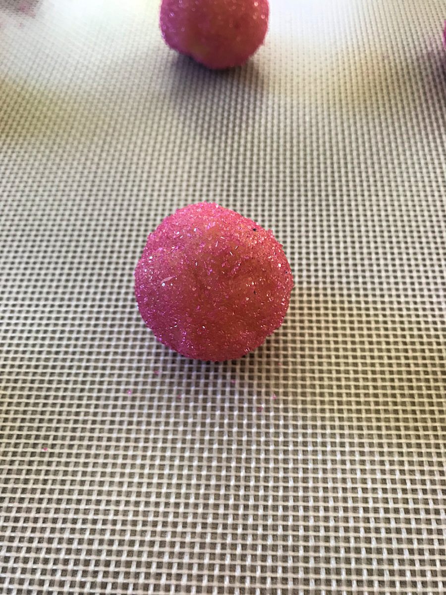 close up of pink cookie dough ball rolled into sprinkles