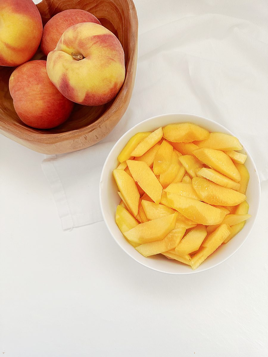 bowl of sliced and whole peaches