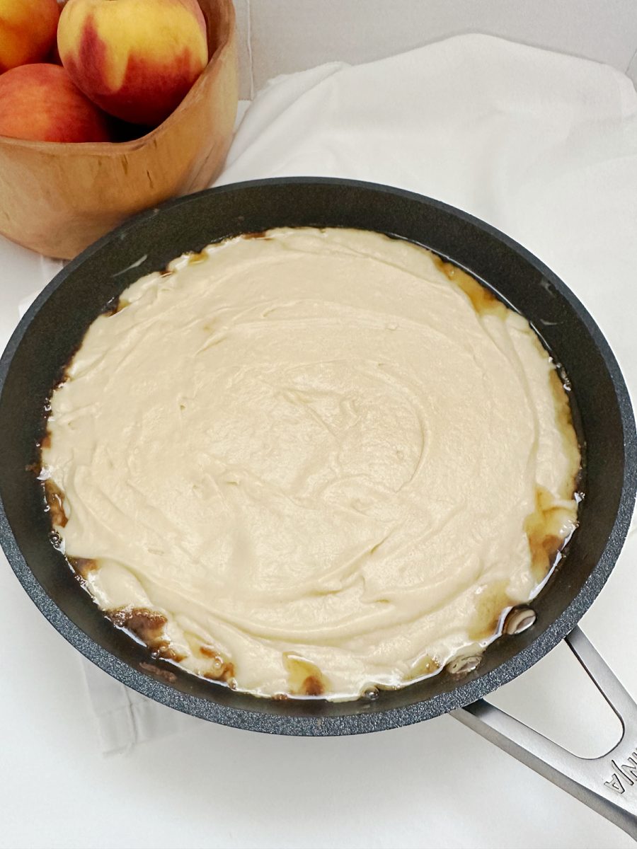 cake batter with peaches in skillet