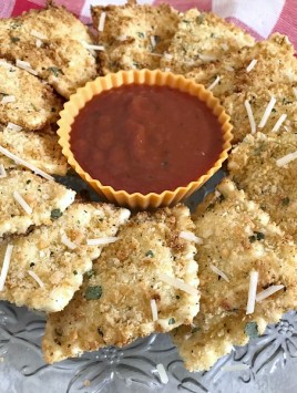 Air Fryer Fried Ravioli on a crystal plate with marinara dipping sauce, with a red checkered towel