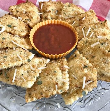 Air Fryer Fried Ravioli on a crystal plate with marinara dipping sauce, with a red checkered towel