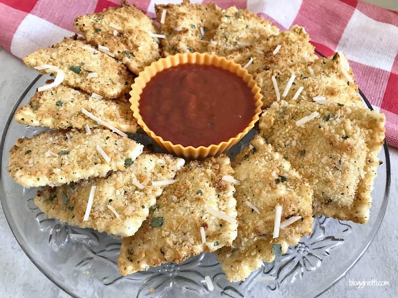 Air Fryer Fried Ravioli on a crystal plate with marinara dipping sauce, with a red checkered towel