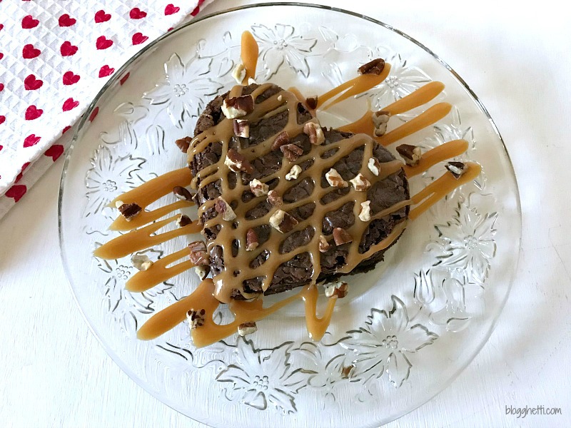 These Caramel Drizzled Brownie Hearts are ready to be served on a crystal plate