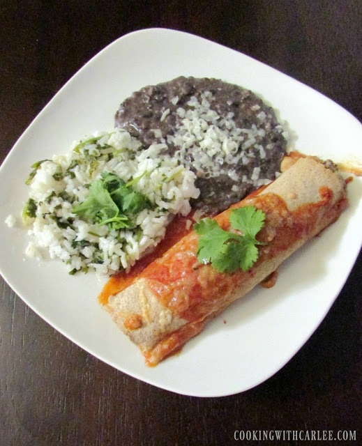 Chicken enchiladas on a white plate with rice and beans