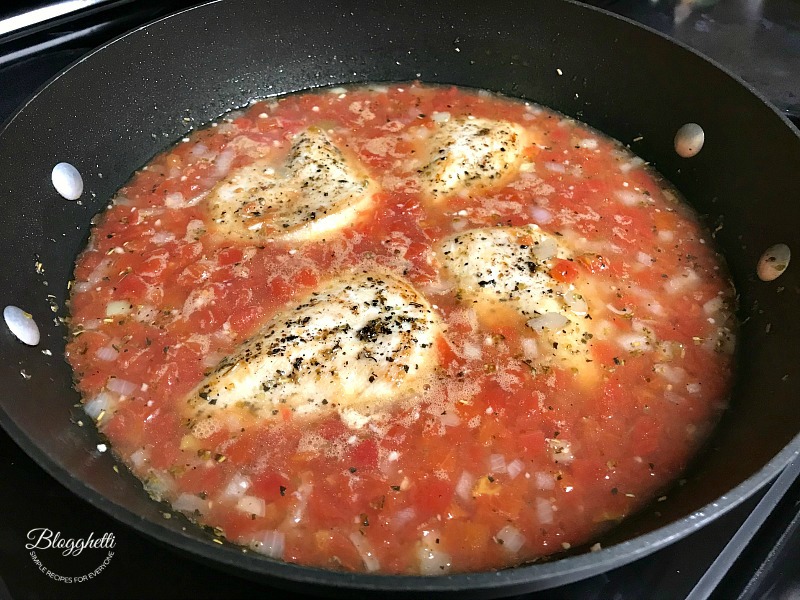 Chicken simmering in tomato orzo sauce