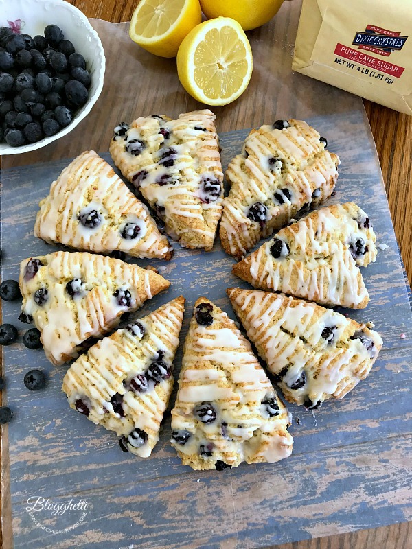 lemon blueberry scones pictured with a bowl of blueberries and a cut lemon