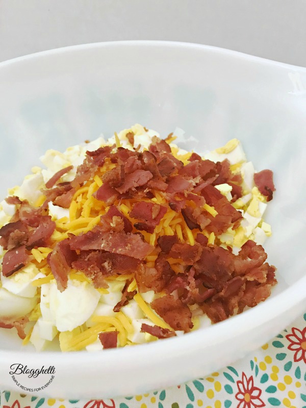 Bacon Cheddar Egg Salad in white bowl on top of a flowered towel