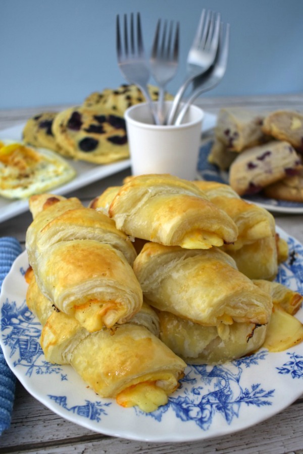 Ham and cheese croissants on plate with breakfast foods in the background