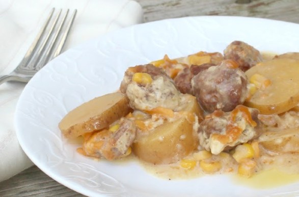 serving of slow cooker potato, brats, corn, and cheese casserole on a white plate