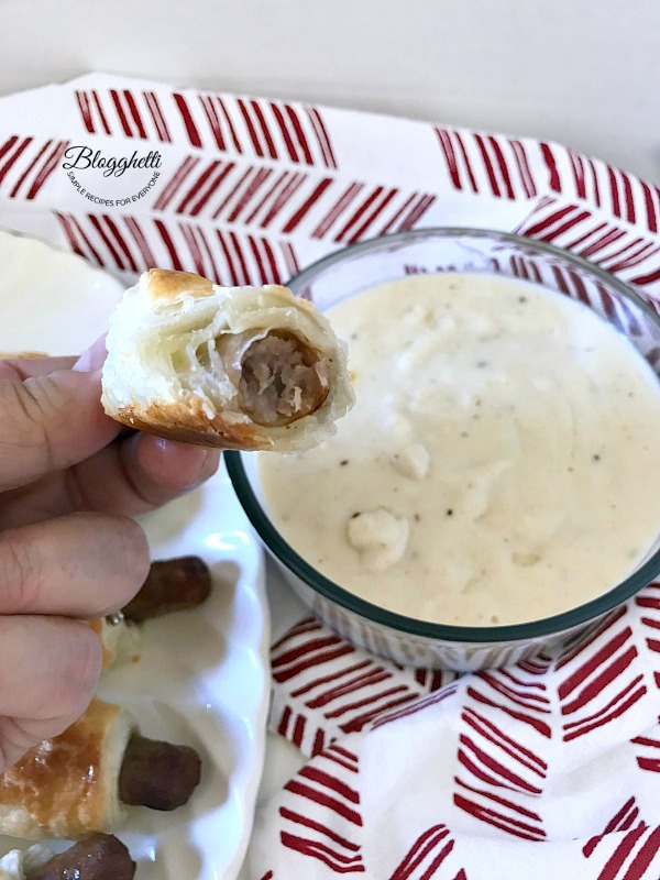 Sausage dipper with bite take out of it with white gravy