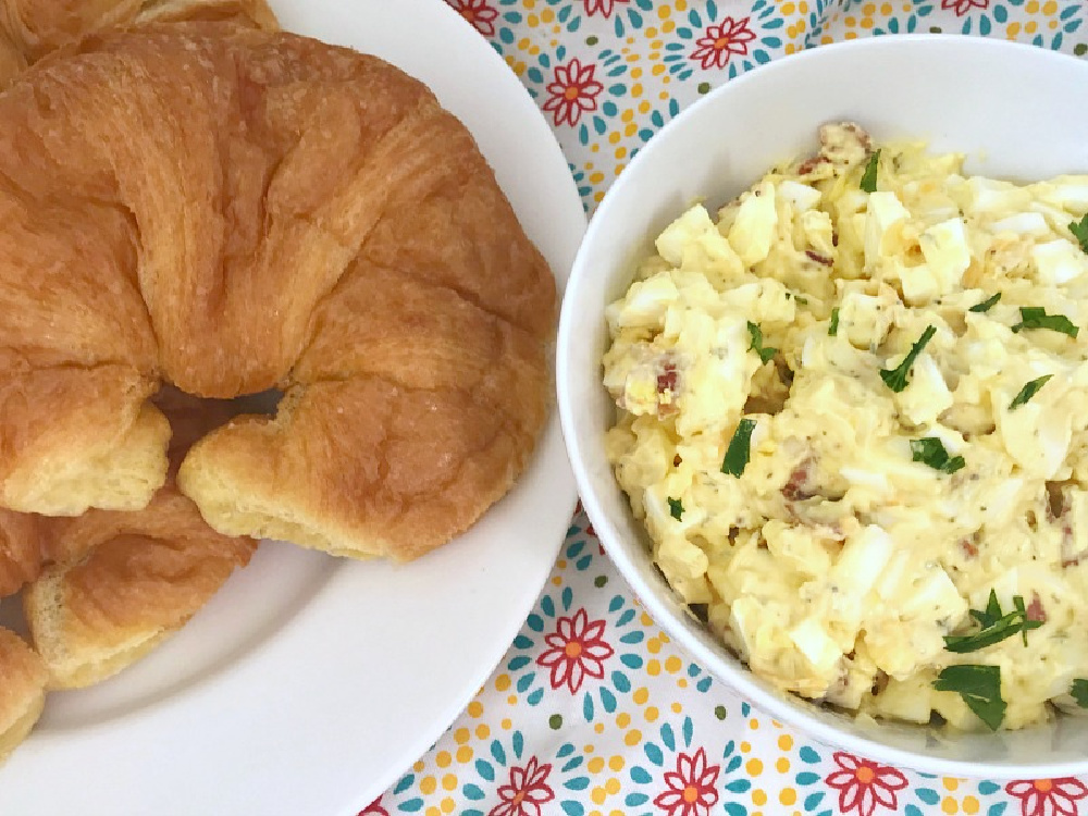 bacon cheddar egg salad in bowl with plate of croissants