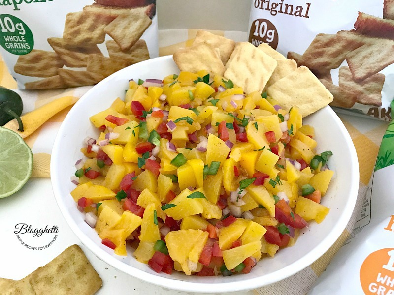 Bowl of homemade peach salsa with cornbread crisps to dip