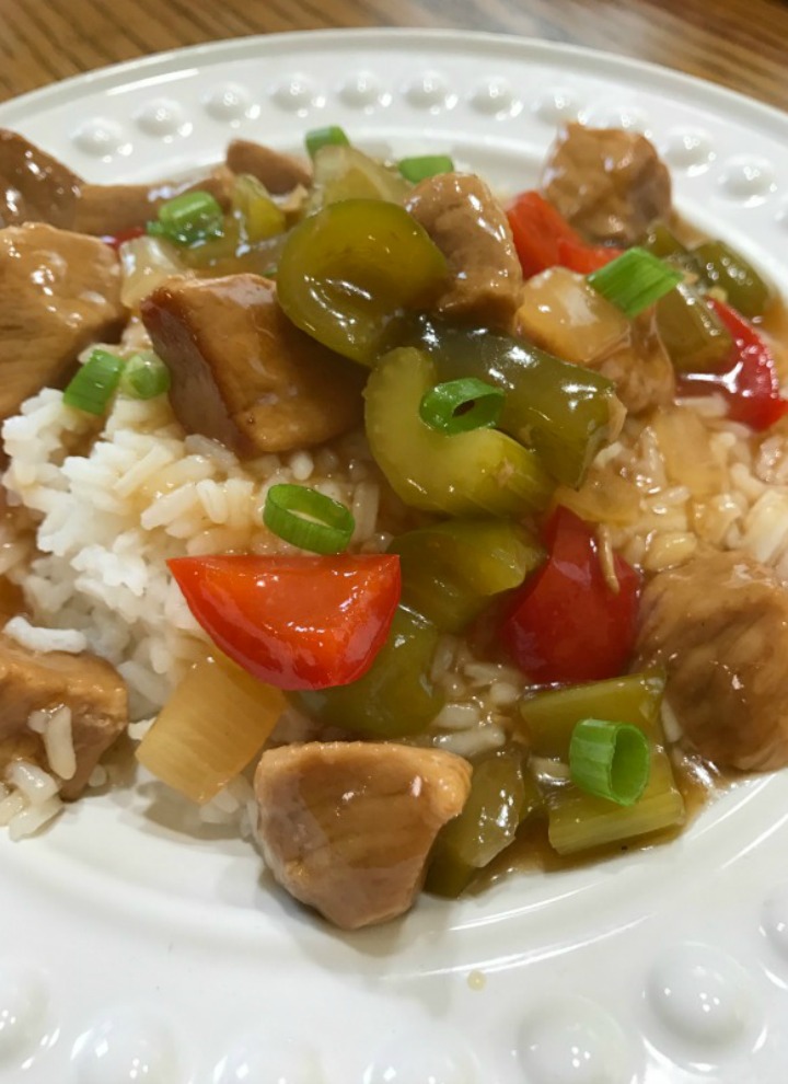 Sweet and Sour Pork served over white rice on a white plate