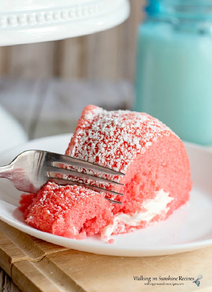 slicing into a piece of Strawberry Bundt Cake with Marshmallow creme filling on a white plate