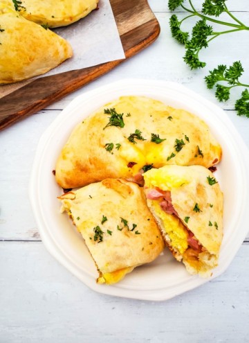 white plate with ham, egg, and cheese breakfast calzones