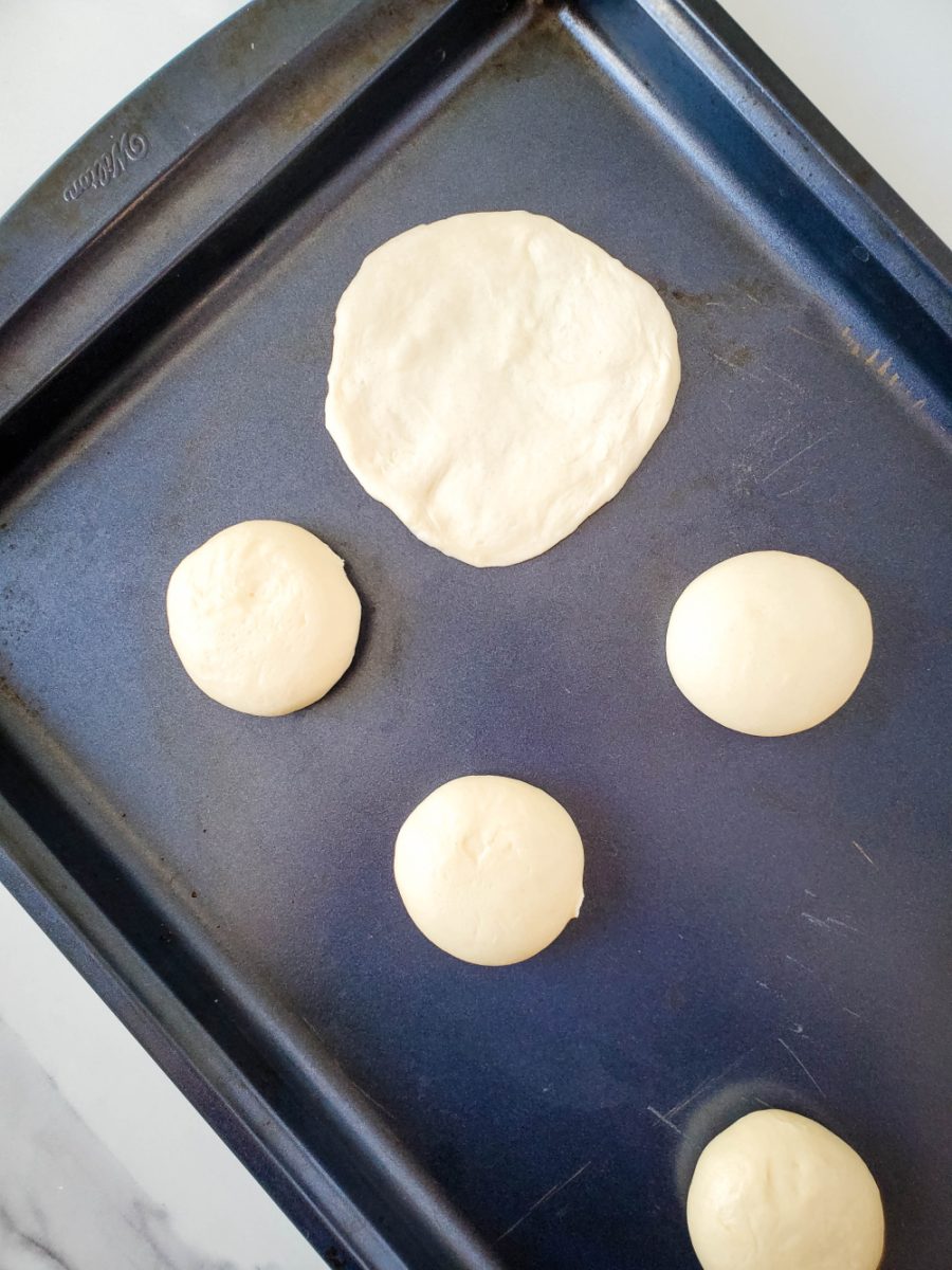 flattening dough into circle on baking sheet