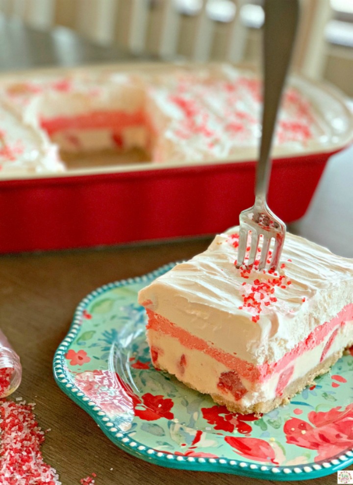 Slice of No Bake strawberry lasagna on a teal flowered plate with the cake pan in the background
