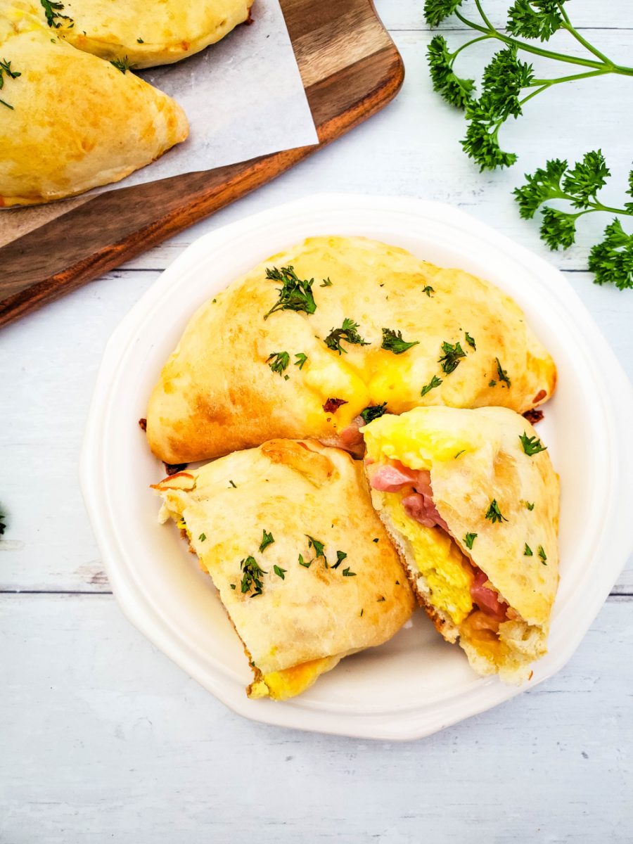 white plate with ham, egg, and cheese breakfast calzones