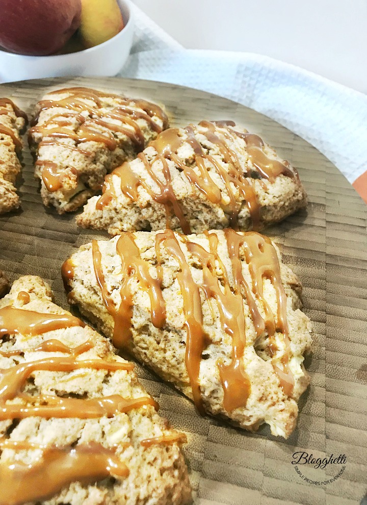 Caramel Apple Scones on a wooden platter with bowl of apples in the background